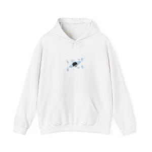 Op de afbeelding: Witte hoodie met een voorzak en een trekkoord. Het ontwerp toont een zwarte en blauwe planeet met een ring, omgeven door een lichtblauw wolkenachtig ontwerp. De hoodie heeft een casual stijl.