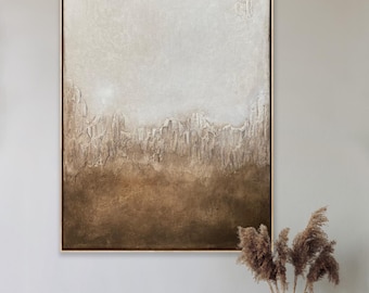 May include: Abstract textured wall art in a gold frame. The artwork features a gradient of colors, transitioning from a light beige at the top to a deep brown at the bottom. The textured surface adds depth and visual interest to the piece.