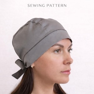 Puede incluir: Patrón de costura de bandana para adultos gris. La bandana es gris con un ribete cosido negro y un lazo en el lateral. El texto "Adult Bandana" y "SEWING PATTERN" se muestra en la imagen.