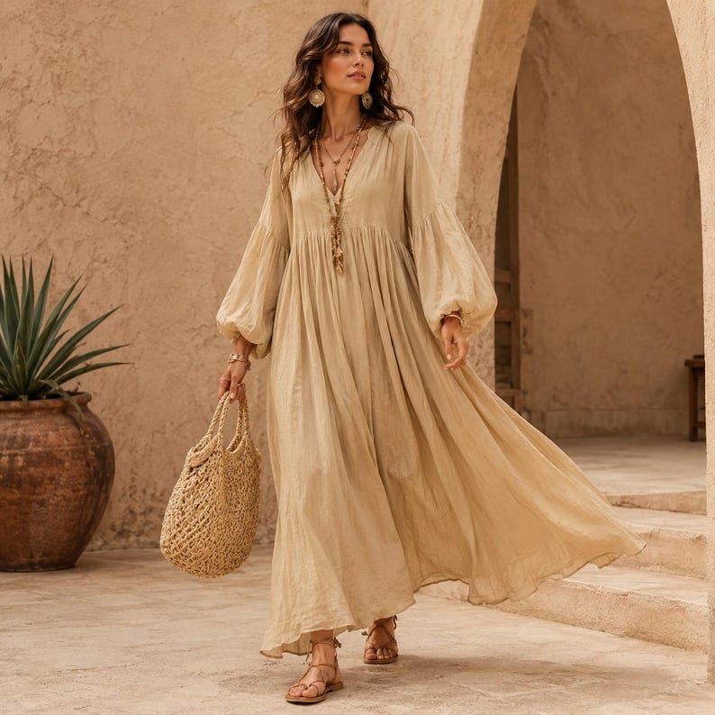 K&ouml;nnte beinhalten: Ein beiges, bodenlanges Kleid mit langen &Auml;rmeln, V-Ausschnitt und geraffter Taille, kombiniert mit einer geflochtenen Strohtasche und braunen Riemchensandalen. Das Kleid zeichnet sich durch volumin&ouml;se &Auml;rmel und einen flie&szlig;enden Rock aus.