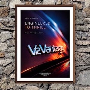 May include: Framed Aston Martin poster with the text "Engineered to Thrill." The poster features the V12 Vantage logo and the Aston Martin wings emblem. The background has a gradient of blue, orange, and red.