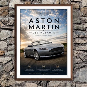 May include: Framed print featuring an Aston Martin DB9 Volante. The image showcases a silver convertible car with the text "ASTON MARTIN" and "DB9 VOLANTE". The poster includes the words "BEAUTY. POWER. SOUL." and other text.