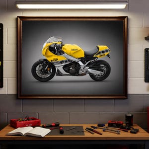 Könnte beinhalten: Gerahmter Druck eines gelb-schwarzen Yamaha-Motorrads. Das Motorrad hat ein schlankes Design mit dem Wort "GP" an der Seite. Das Bild wird in einer Werkstatt mit Werkzeugen und Ausrüstung angezeigt.