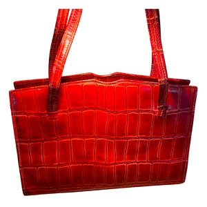 Könnte beinhalten: Eine leuchtend rote Handtasche mit Krokodilleder-Textur. Die Tasche hat zwei Henkel und eine rechteckige Form. Das Leder wirkt glänzend. Die Tasche ist im Shopper-Stil.