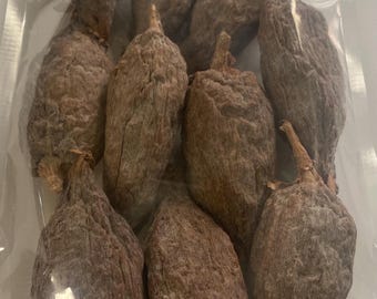 May include: A clear plastic bag containing ten dried, brown, wrinkled persimmons. Each fruit has a small, woody stem at the top and a textured, dusty surface. The fruits are arranged in a cluster within the transparent packaging.