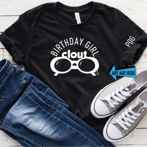 May include: Black t-shirt with the words "BIRTHDAY GIRL clout" and a pair of white glasses. The shirt is paired with blue jeans and gray sneakers. The text "ANY AGE HERE" is on a blue arrow.