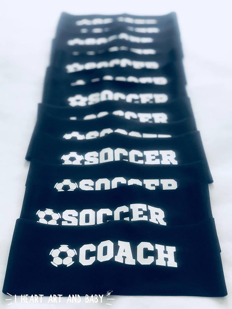 以下が含まれることがあります： 白いサッカーボールと「SOCCER」または「SOCCER COACH」の文字が書かれた黒いヘッドバンドのスタックです。