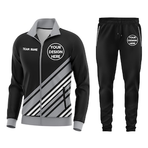 May include: Black athletic tracksuit with a jacket and matching pants. The jacket features a gray collar, cuffs, and diagonal stripes. Text on the jacket reads "TEAM NAME" and "YOUR DESIGN HERE". The pants have a drawstring and the text "YOUR DESIGN HERE".