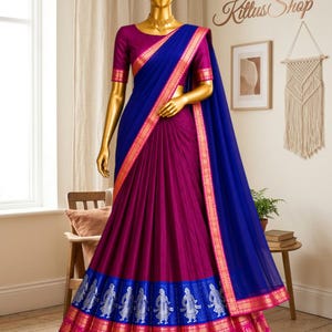 May include: A traditional Indian sari in shades of purple and blue, displayed on a mannequin. The sari features intricate gold and silver detailing along the borders and a matching blouse. The text "Kittus Shop" is visible in the background.