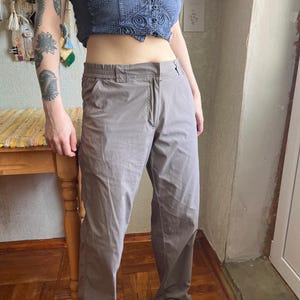 Op de afbeelding: Een effen taupekleurige broek met een platte voorkant, een knoop- en ritssluiting en een elastische tailleband. De broek heeft een recht model met zijzakken en is gemaakt van een glad, lichtgewicht materiaal.