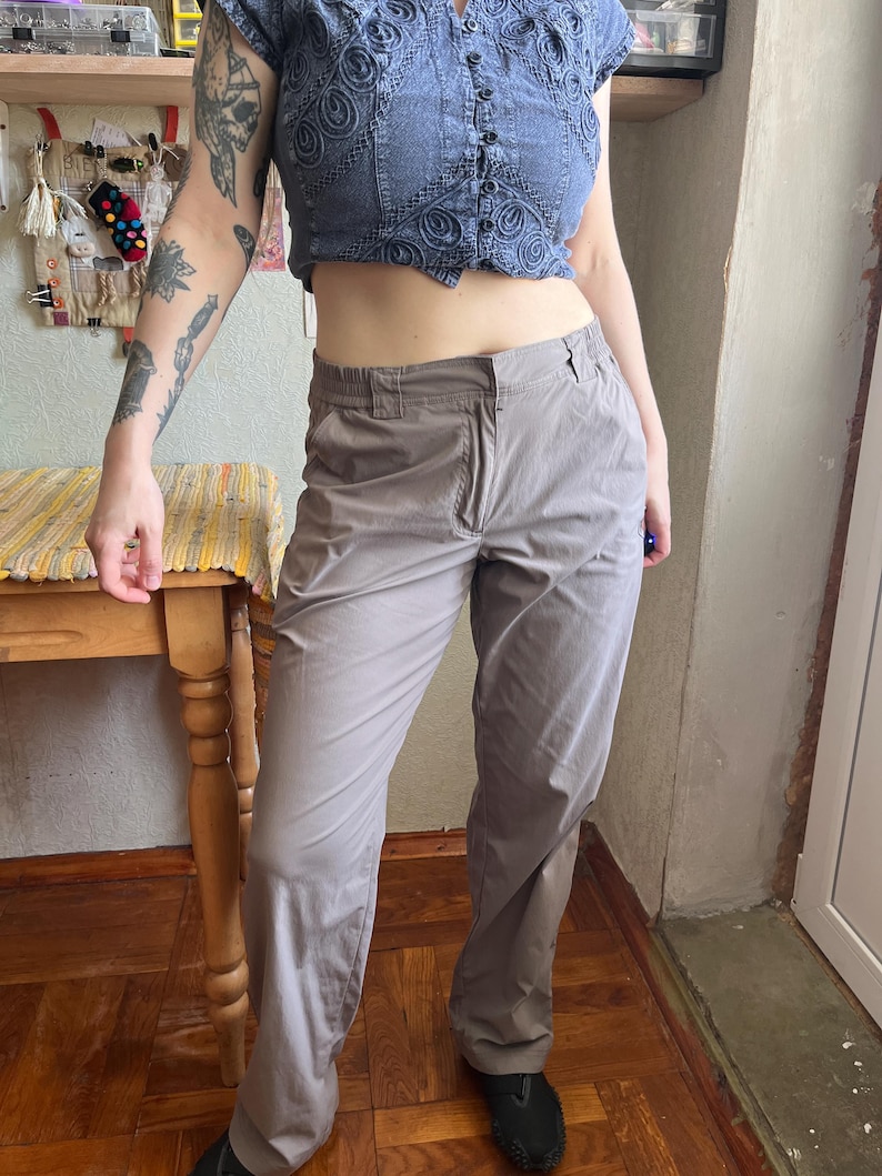 Op de afbeelding: Effen taupekleurige broek met een rechte snit, een standaard tailleband met riemlussen, een ritssluiting aan de voorzijde en zijzakken. De broek is gemaakt van een gladde, lichtgewicht stof met een subtiele glans.