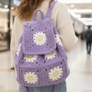 Peut inclure: Un sac à dos crocheté à la main, de couleur violet clair, orné de marguerites blanches et crème. Le sac est doté d'un rabat, de bretelles réglables et d'une poignée supérieure. Ce sac à dos unique sur le thème floral est parfait pour transporter l'essentiel.