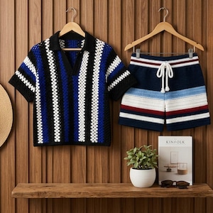 May include: A matching crochet polo shirt and shorts set in blue, black, and white stripes hangs on a wooden hanger. The shorts have a drawstring waist. A straw hat and a shelf with a plant and book are also visible.