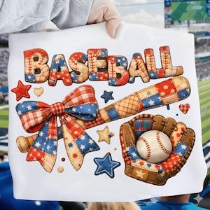 Op de afbeelding: Een wit t-shirt met een grafisch ontwerp met het woord BASEBALL in een patchworkpatroon van rood, wit en blauw. Het ontwerp bevat een grote strik, een honkbalknuppel, een honkbalhandschoen met een bal, en diverse ster- en hartvormen.