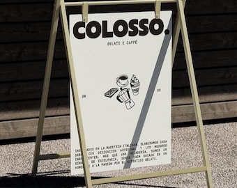 May include: A-frame sign with the word "COLOSSO" in bold black letters, advertising gelato and coffee. The sign features illustrations of coffee, gelato, and a coffee maker. The sign is supported by a light beige metal frame.