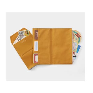 Puede incluir: Organizador de lona color mostaza con múltiples bolsillos y cierre de solapa. El organizador está abierto, revelando varias tarjetas, boletos y un posavasos. El diseño es simple y funcional.