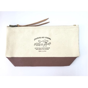 May include: A rectangular canvas pouch with a brown bottom and a cream-colored upper section. The pouch has a zipper closure and leather pull tabs. The text "STANDARD AND STRONG THE SUPERIOR LABOR" is printed on the front.