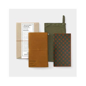 Op de afbeelding: Een briefpapierset met een bruin leren notitieboek, een groen en bruin geruit notitieboek, een groene stoffen etui en een bruin papieren verpakking. De verpakking en de kaften van de notitieboeken hebben de tekst "TRAVELER'S notebook" en "ACE HOTEL".