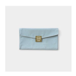 Puede incluir: Una cartera de lona azul claro con un parche de cuero marrón que dice "TO & FRO TRAVELER'S COMPANY" en letras blancas.