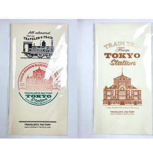May include: Two cream-colored Traveler's Factory notebooks. One features a train illustration and the text "All aboard, Get on TRAVELER'S TRAIN" and "TOKYO STATION MARUNOUCHI". The other says "TRAIN TRIP From TOKYO Station" with a building illustration.