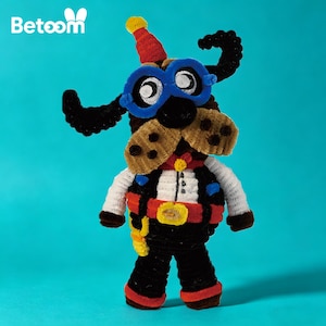 Peut inclure: Une figurine de chien faite à la main en cure-pipe, portant des lunettes bleues, un chapeau rouge et un gilet. Le chien a un museau et des oreilles bruns, et porte une tenue noire avec une ceinture rouge et jaune. Sur fond bleu sarcelle.
