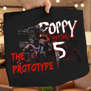 Könnte beinhalten: Schwarzes T-Shirt mit dem Text "Poppy Playtime 5" in Weiß und Rot, sowie einer Grafik einer mechanischen Kreatur. Die Worte "The Prototype" sind ebenfalls rot. Das Design beinhaltet eine detaillierte Illustration einer Roboterfigur.