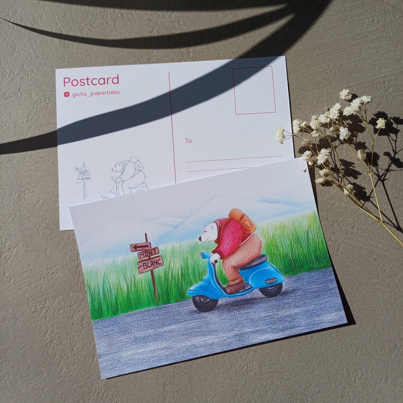 Może przedstawiać: Poczt&oacute;wka z ręcznie rysowaną ilustracją niedźwiedzia na niebieskim skuterze, zmierzającego w stronę znaku z napisem "Mont Blanc". Tył poczt&oacute;wki ma miejsce na adres i znaczek. Ilustracja na tle zielonej trawy i pasma g&oacute;rskiego.