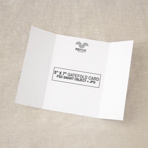 Puede incluir: Una tarjeta gatefold blanca con el texto 5" X 7" GATEFOLD CARD PSD SMART OBJECT + JPG en un marco rectangular negro, y un logotipo negro arriba que dice PSYCHE MOCKUPS. La tarjeta está abierta, mostrando tres paneles sobre un fondo neutro.