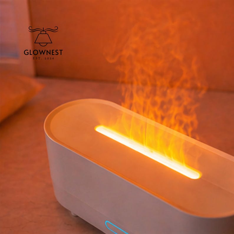 May include: A white and orange electric fireplace with a flame effect. The product has a rectangular shape with rounded edges and a glowing orange light emanating from the top. The brand name "GLOWNNEST" is visible in the upper left corner.