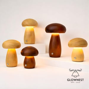 May include: A collection of mushroom-shaped lamps in various shades of wood, from light to dark brown. Each lamp has a rounded cap and a cylindrical stem, with a warm, inviting glow emanating from within. The lamps are arranged on a white surface.