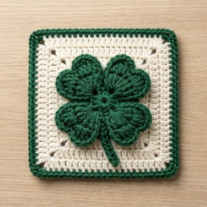 May include: A square, crocheted coaster featuring a four-leaf clover design. The clover is a vibrant green, centered on a cream-colored square, with a green border. The handmade coaster is perfect for St. Patrick's Day.
