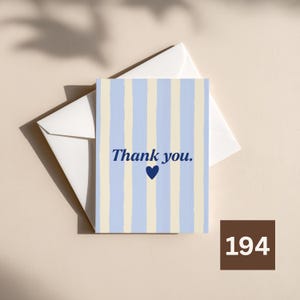 May include: A rectangular greeting card featuring vertical stripes in light blue and cream. The text "Thank you." is printed in dark blue in the center, positioned above a small dark blue heart. The card is placed on top of a white envelope.