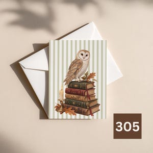 May include: A greeting card featuring a barn owl perched on a stack of five vintage-style books, next to a lit candle in a brass holder. The background has vertical light green and white stripes, and the card rests on a white envelope.