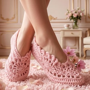 May include: Pale pink crochet slippers with a floral pattern. The slippers are decorated with pink flowers and are placed on a pink rug with scattered rose petals. The image suggests comfort and relaxation.