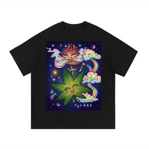 Può includere: T-shirt nero con grafica colorata. Il design presenta una foglia di cannabis con un volto, un fungo con un volto, nuvole arcobaleno e stelle, in stile psichedelico.