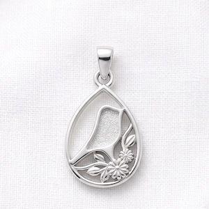 May include: A silver-toned pendant in a teardrop shape featuring a cutout silhouette of a bird perched on a branch with small flowers and leaves. The bird figure has a textured matte finish, while the outer frame and floral details are polished.