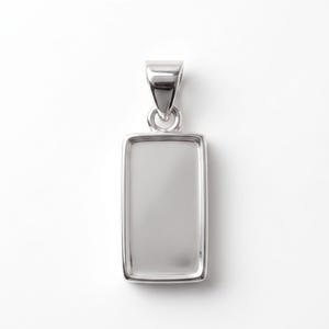 May include: A polished silver rectangular pendant. The pendant features a rectangular frame and a loop for a chain. The design allows for a small insert to be placed within the frame.