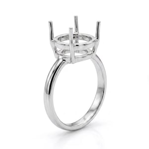 May include: A silver ring setting with a round top and four prongs to hold a gemstone. The ring has a smooth, polished band and is designed for jewelry making.