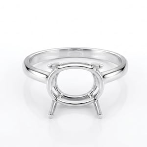 Peut inclure: Un sertissage de bague en argent poli avec un centre ovale et quatre griffes. L'anneau de la bague est lisse et arrondi. Le sertissage est conçu pour contenir une pierre précieuse. La bague est présentée sur fond blanc.