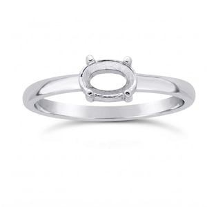Könnte beinhalten: Ein silberner Ring mit ovaler Fassung. Der Ring hat einen schlichten Band und vier Krappen, um einen Edelstein zu halten. Der Ring wird vor weißem Hintergrund gezeigt.