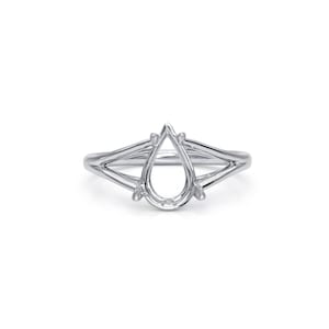 Puede incluir: Un anillo de plata con un engaste en forma de pera. El anillo presenta un diseño de caña dividida, con dos bandas que se fusionan cerca del engaste. El engaste está diseñado para sostener una piedra preciosa. El anillo está sobre un fondo blanco.