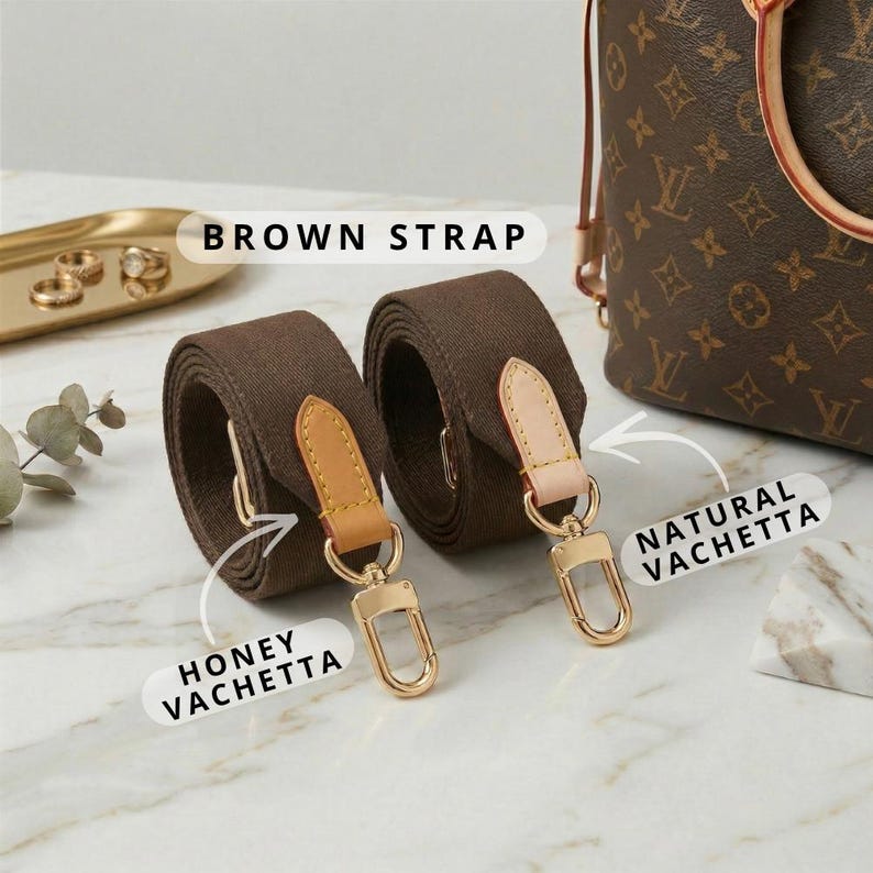 Op de afbeelding: Twee bruine canvas tasriemen met honing- en natuurlijk vachetta lederen accenten en goudkleurige hardware. De riemen zijn opgerold en tonen hun textuur en ontwerp. De tekst "BROWN STRAP" is zichtbaar.