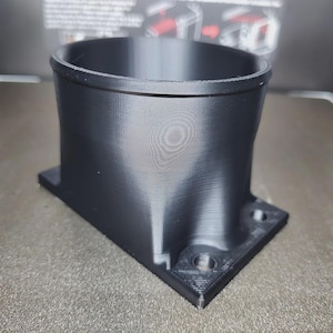 Op de afbeelding: Een witte keramische mok met een zwart handvat en de tekst "But First, Coffee" in een vetgedrukte, zwarte letter. De mok staat tegen een vage achtergrond, wat een gezellige setting suggereert.