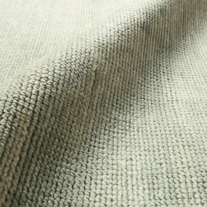 May include: A light gray area rug with a dense, looped pile texture. The surface features a consistent, uniform weave pattern with subtle tonal variations in the gray fibers, creating a soft, tactile appearance across the folded fabric.