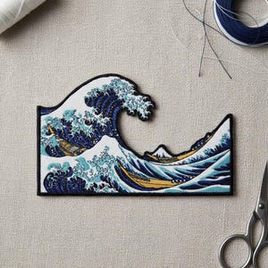 May include: Embroidered patch featuring a stylized depiction of a large ocean wave with boats, inspired by Japanese art. The wave is rendered in shades of blue and white, with a black border. The patch is rectangular.