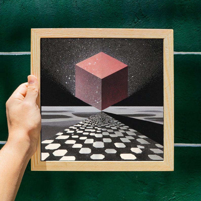 Pode incluir: Uma obra de arte emoldurada com um design geom&eacute;trico. Um cubo vermelho flutua sobre um caminho quadriculado em preto e branco, contra um c&eacute;u estrelado. A obra de arte &eacute; segurada por uma m&atilde;o, com uma moldura de madeira e um fundo verde.