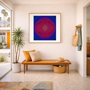 May include: An interior scene with a framed abstract artwork with a red and blue spherical design. A wooden bench with cushions and a woven basket is below the artwork. A potted plant and a rug complete the decor.
