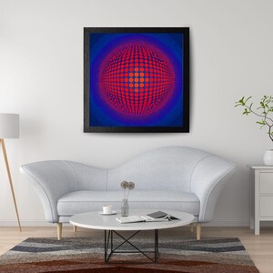 May include: A framed abstract art print with a striking red and blue spherical pattern. The black-framed artwork hangs above a grey sofa and a round coffee table, contributing to a contemporary living room setting.