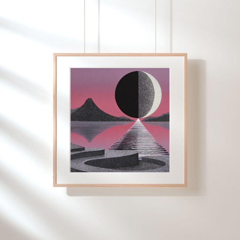 K&ouml;nnte beinhalten: Gerahmter Kunstdruck mit einer surrealen Landschaft mit einer schwarz-wei&szlig;en Kugel, die durch einen Weg &uuml;ber dem Wasser geteilt wird. Das Kunstwerk zeigt eine Bergkette und einen rosa-violetten Himmel. Der Druck ist in einem hellen Holzrahmen.