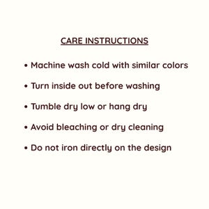 May include: White background with text in a dark brown font. The text reads "CARE INSTRUCTIONS" followed by bullet points detailing washing instructions: machine wash cold, turn inside out, tumble dry low, avoid bleaching, and do not iron on design.